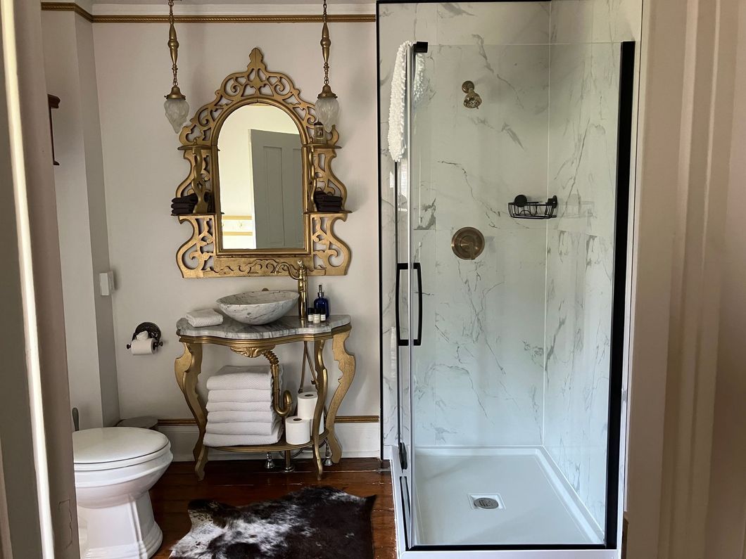 A classic wooden front door with a side window panel, white columns, and a transom window above, framed by brick siding.