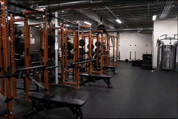 A gym with a lot of exercise equipment and benches