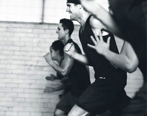 A group of people are running in front of a brick wall.