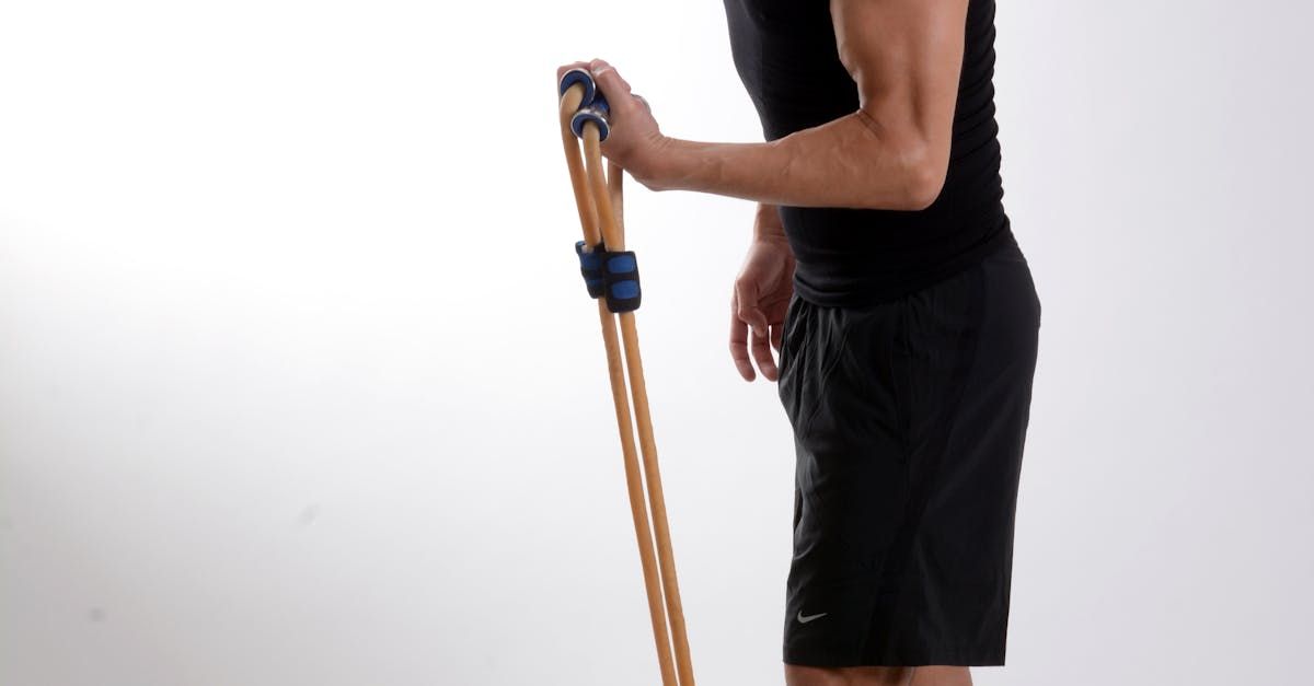 A man in a black tank top and black shorts is holding a wooden pole.