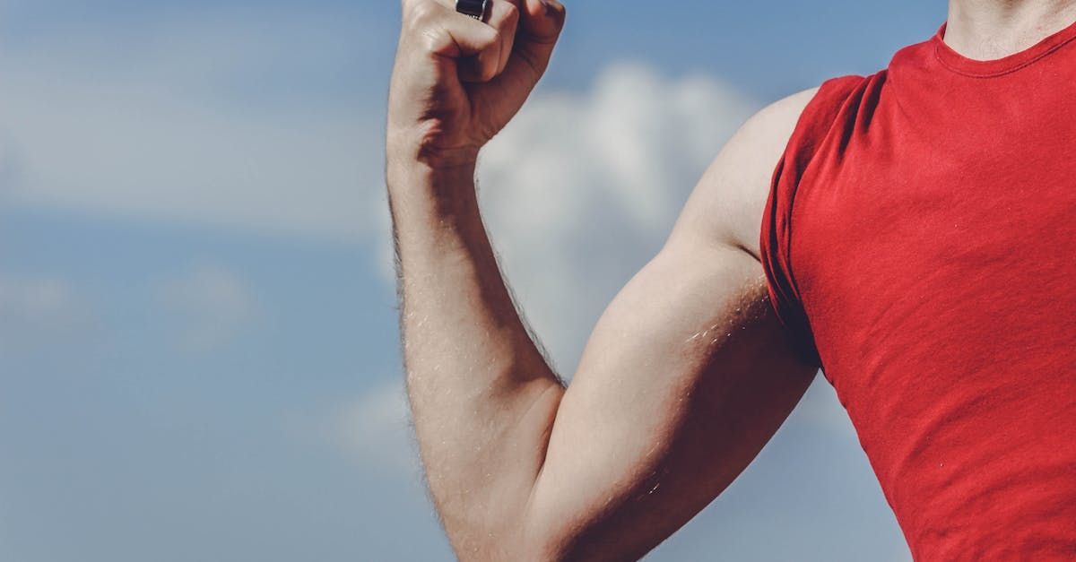 A man in a red tank top is holding a hammer in his hand.