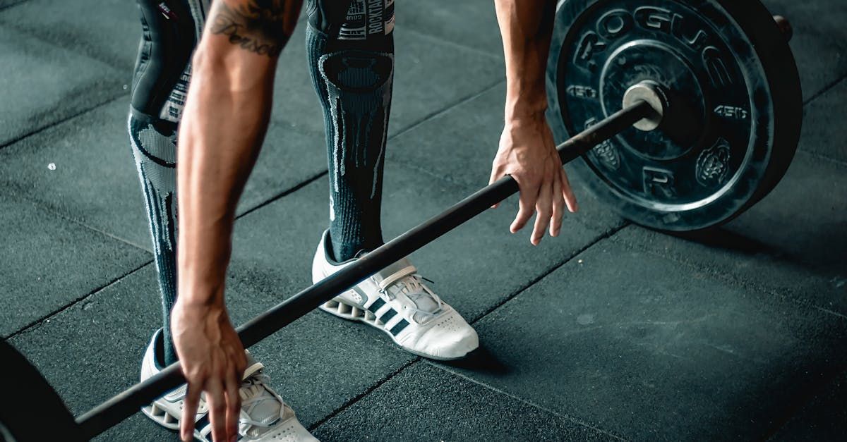 A man is lifting a barbell in a gym.