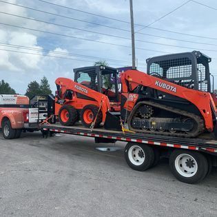 A couple of tractors are sitting on top of a trailer.