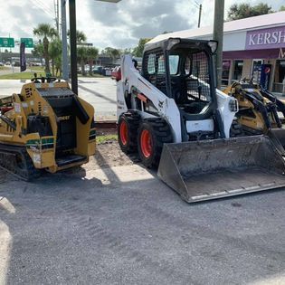 A couple of tractors are parked next to each other on the side of the road.