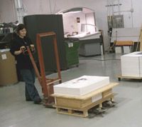 A woman is pushing a pallet with boxes on it in a warehouse.