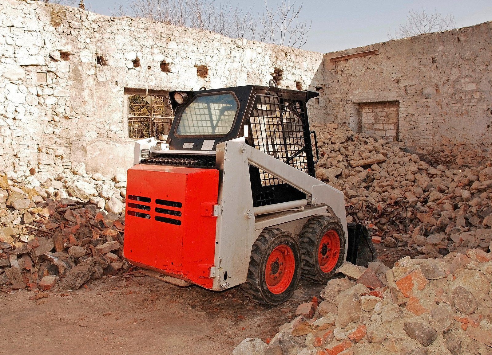 A bobcat skid steer is driving through a pile of rocks.
