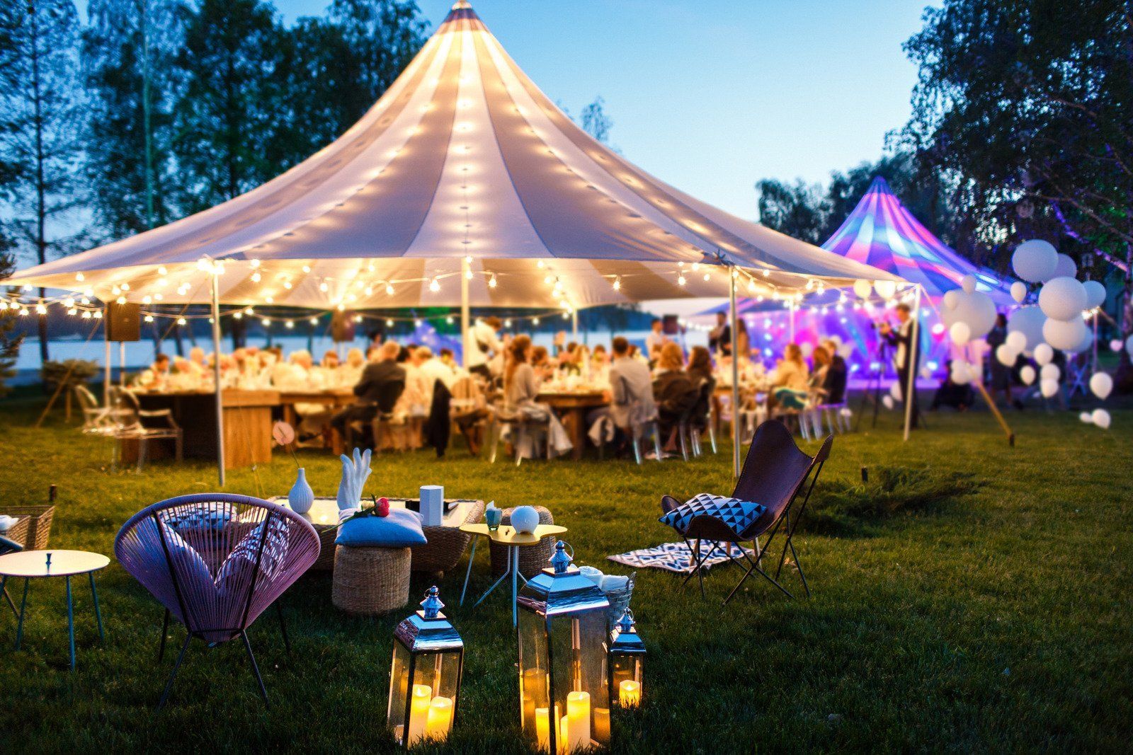 A group of people are sitting at tables under a tent.