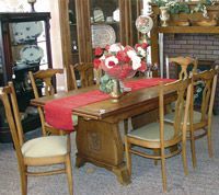 A dining room table and chairs with a vase of flowers on it.