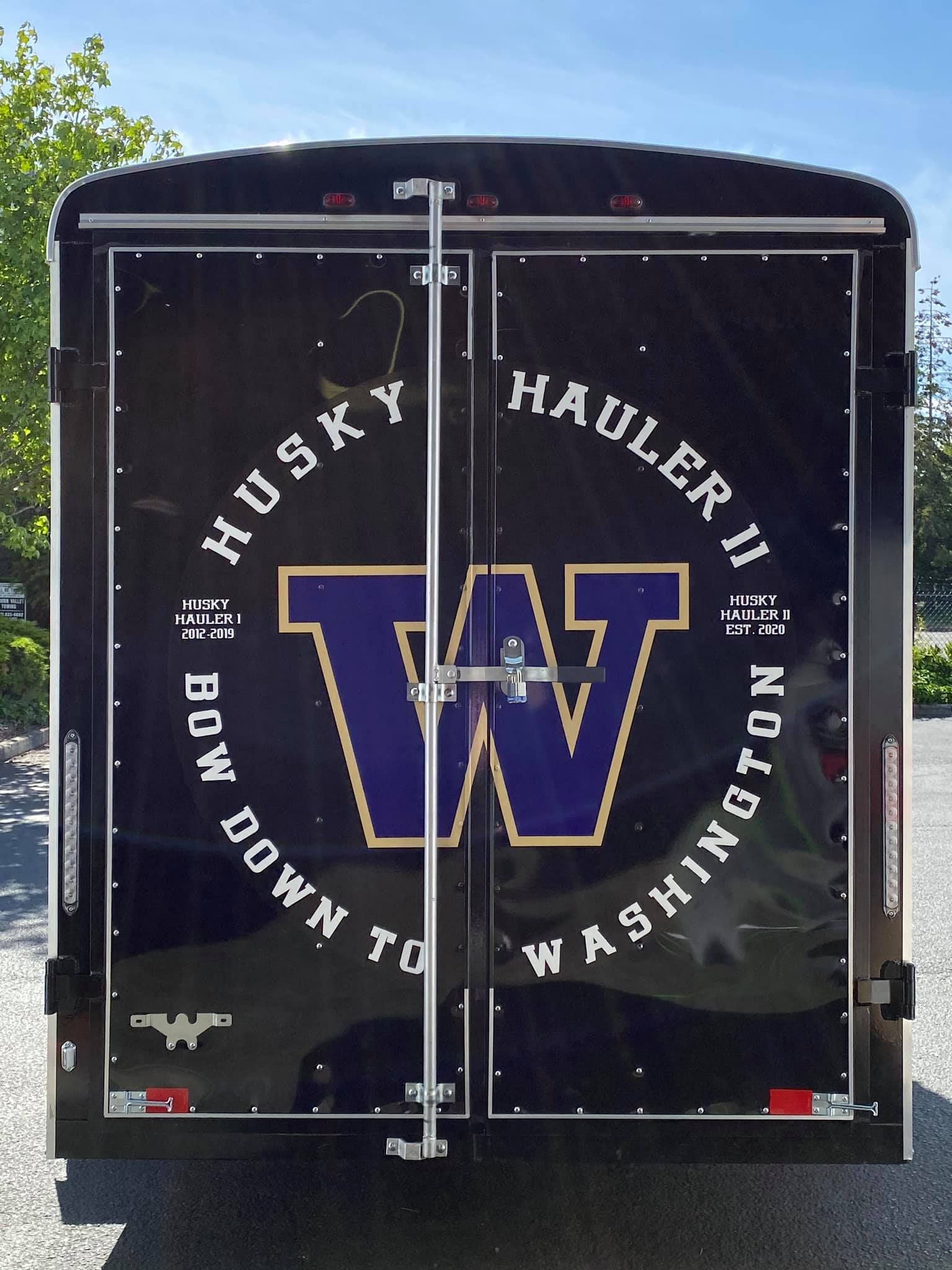 The back of a black cargo trailer featuring a large purple 
