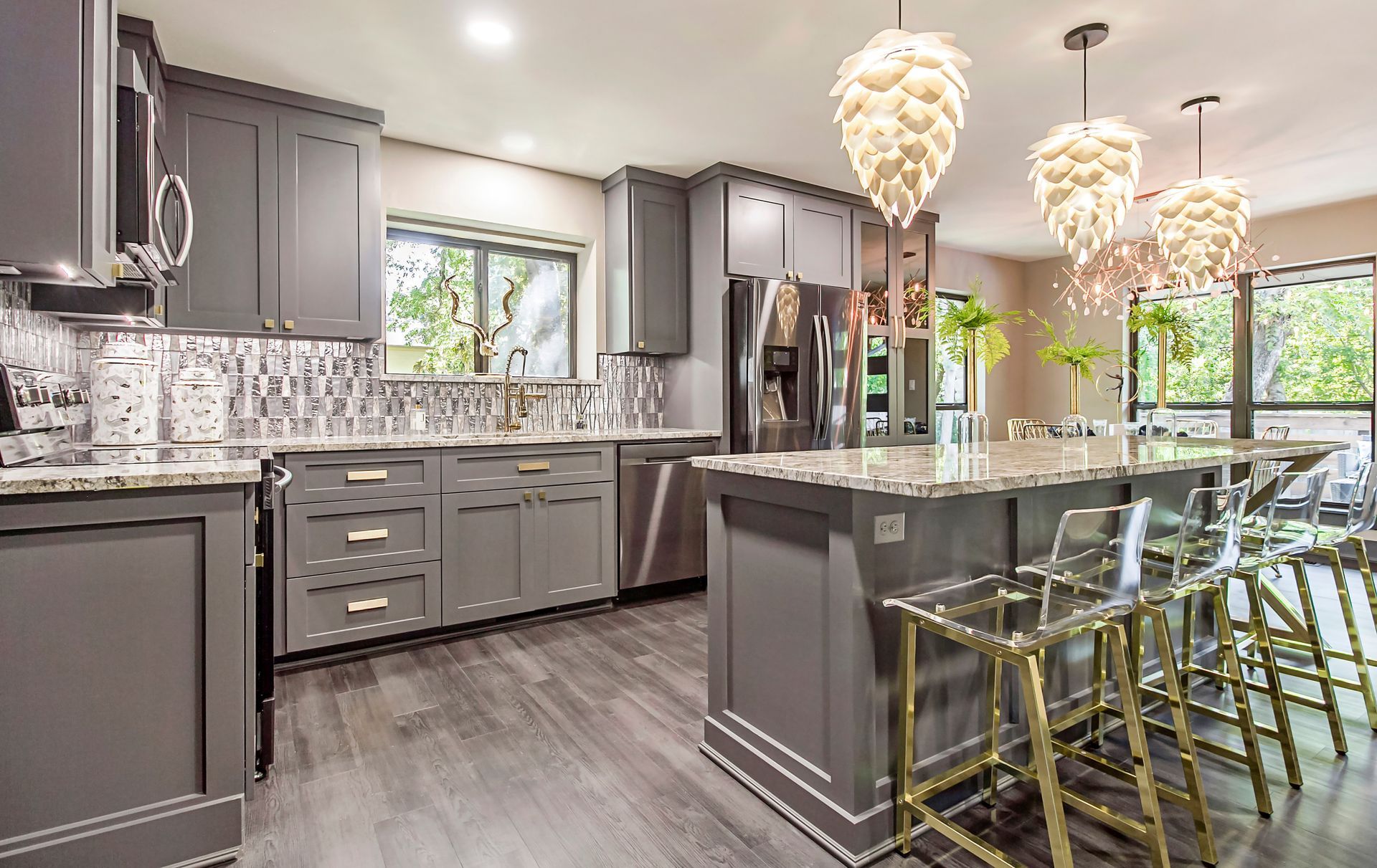 A kitchen with gray cabinets , granite counter tops , stainless steel appliances , and a large island.
