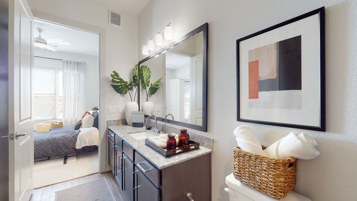 A bathroom with two sinks , a toilet , a mirror and a picture on the wall.