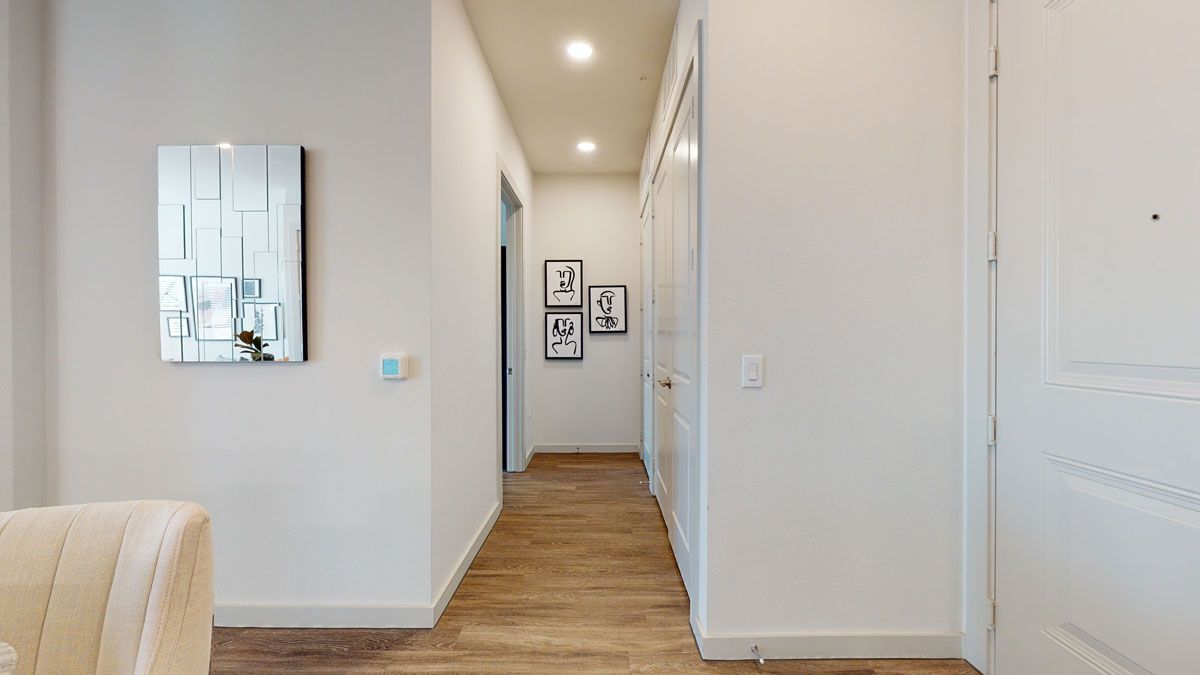 A hallway in a house with a chair and a mirror on the wall.