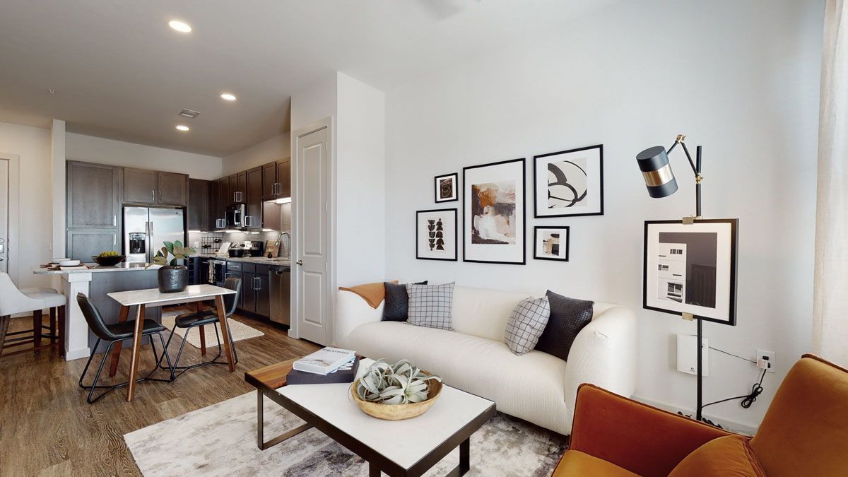 A living room with a couch , chair , coffee table and pictures on the wall.