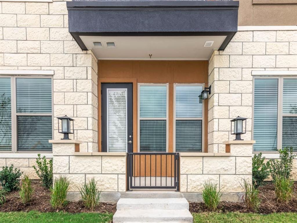 The front door of a brick house with a gate and stairs leading to it.