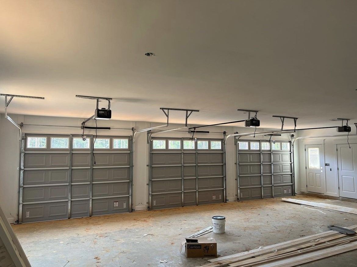 Three garage doors with installed openers inside a partially finished garage.