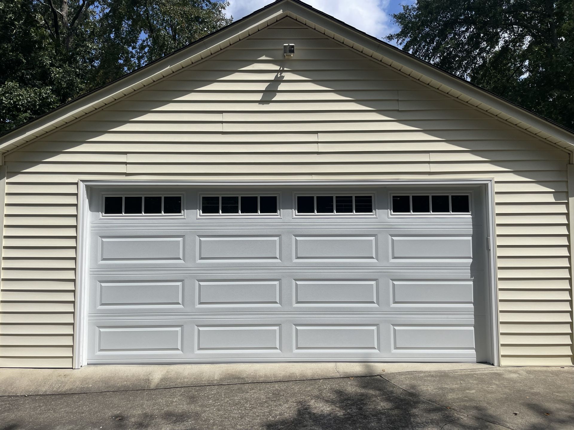 Gray garage door on a light-colored building with horizontal siding.