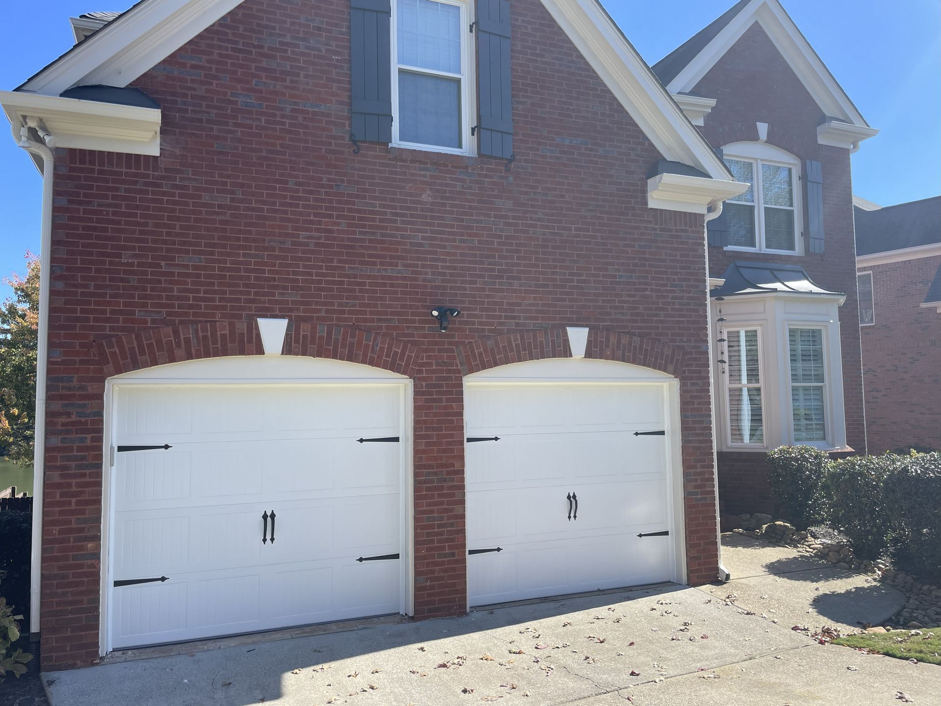 Brick house with two white garage doors and a driveway.