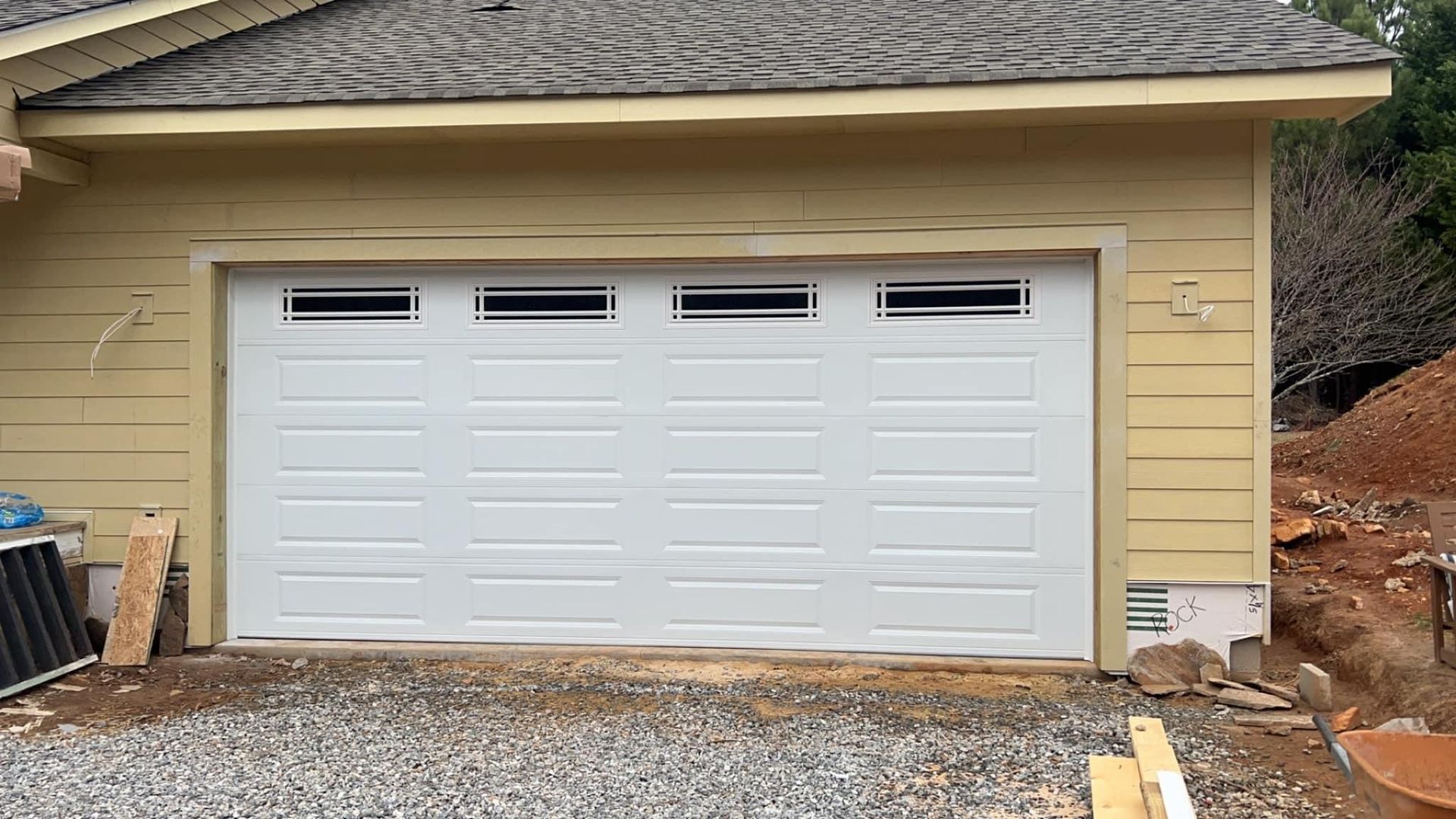 White garage door with four small upper windows in a yellow-sided building.