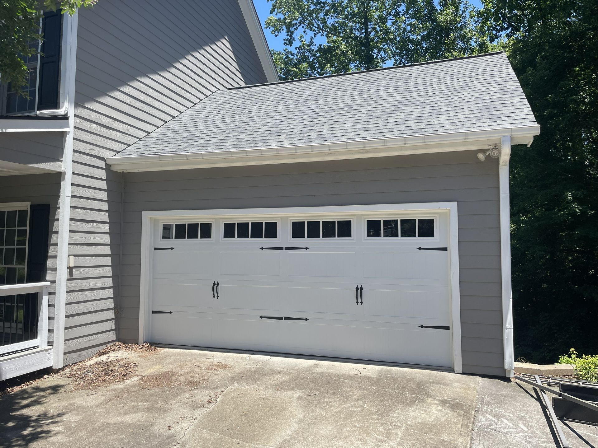 Gray garage with white door and black hardware; asphalt driveway.
