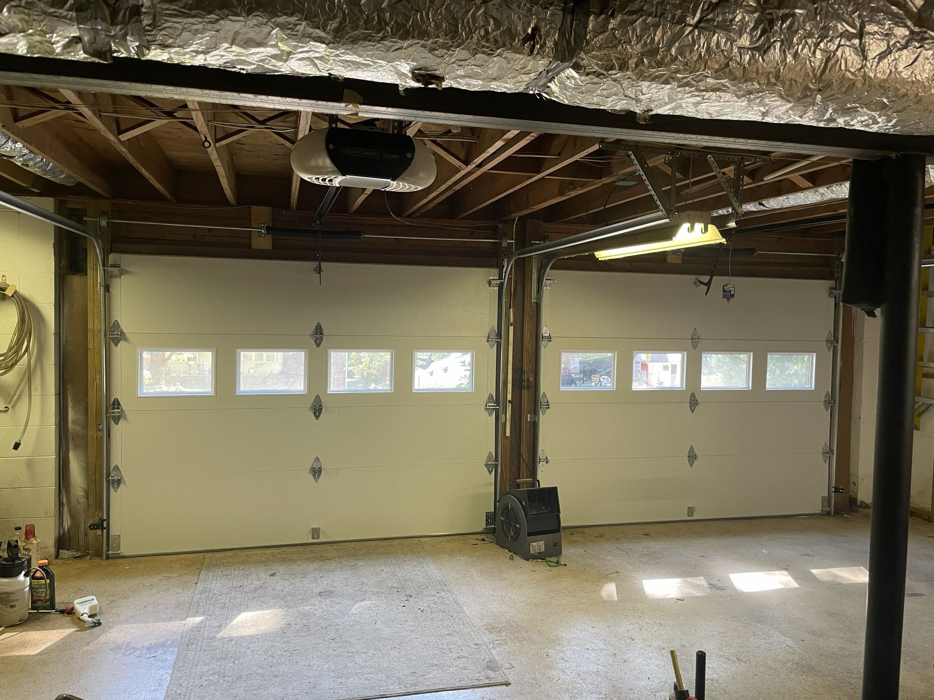 Two white garage doors with windows in a garage.