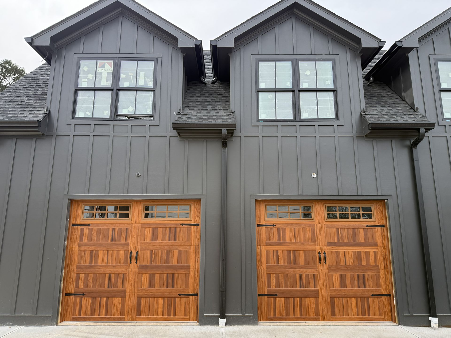 Two-story townhouses with gray siding, brown garage doors, and black-framed windows.