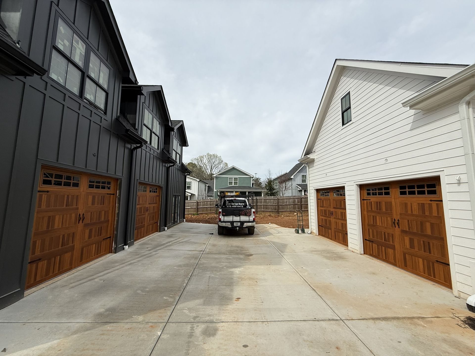Driveway between two buildings with brown garage doors. A truck is parked.