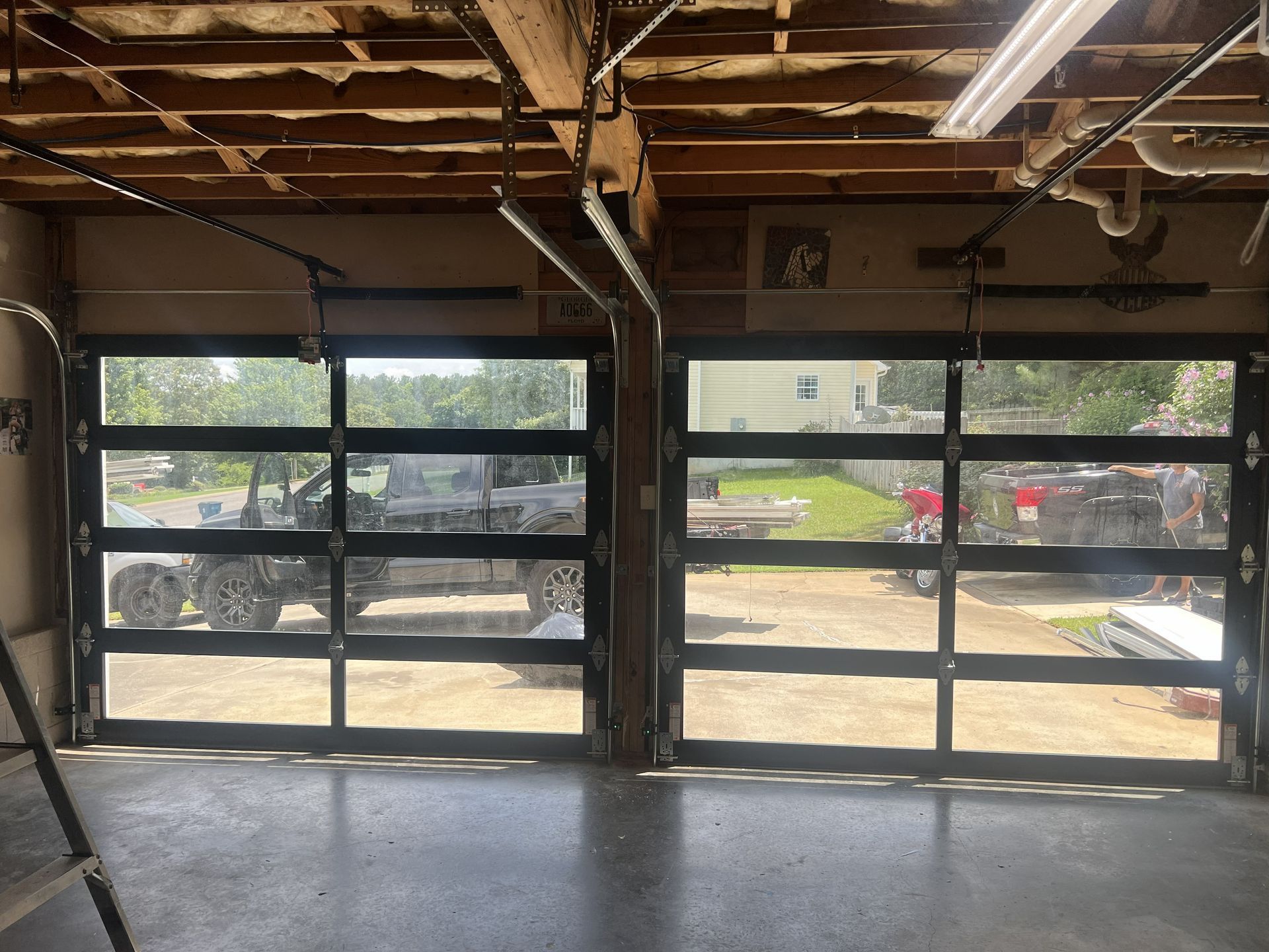 Two garage doors with glass panels; outside view shows truck and lawn.
