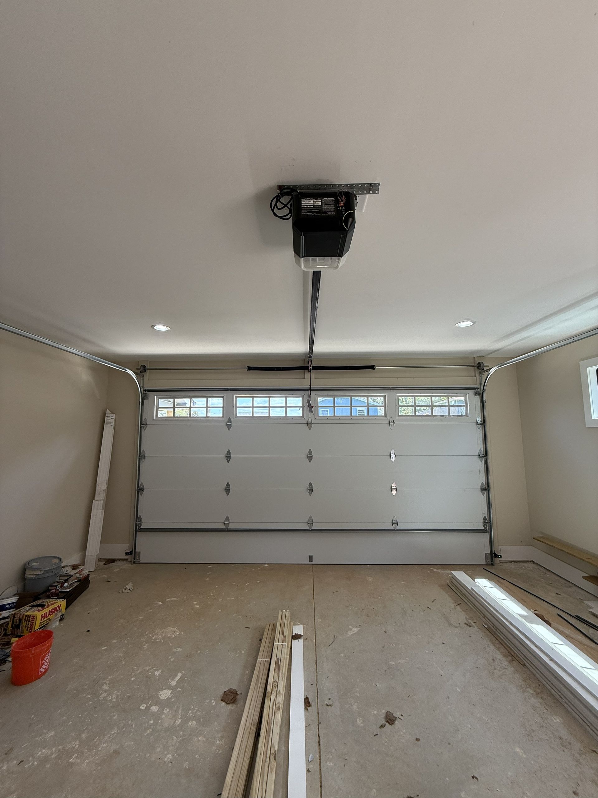 Interior view of a garage with a closed white garage door and a garage door opener.