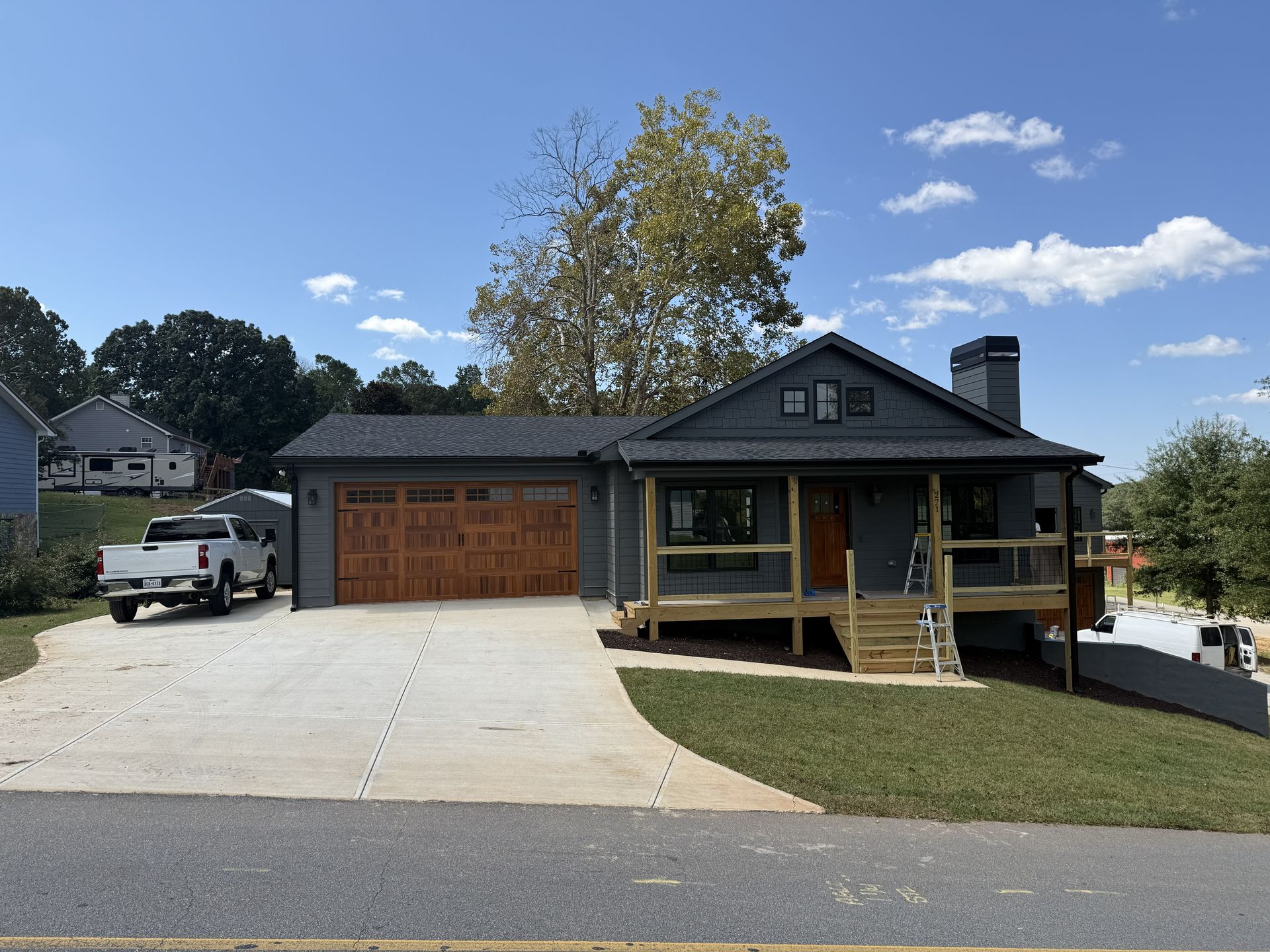 Gray house with a brown garage door and porch, a white pickup truck in driveway.