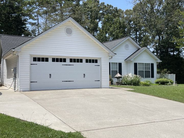 White house with a garage and a driveway on a sunny day.