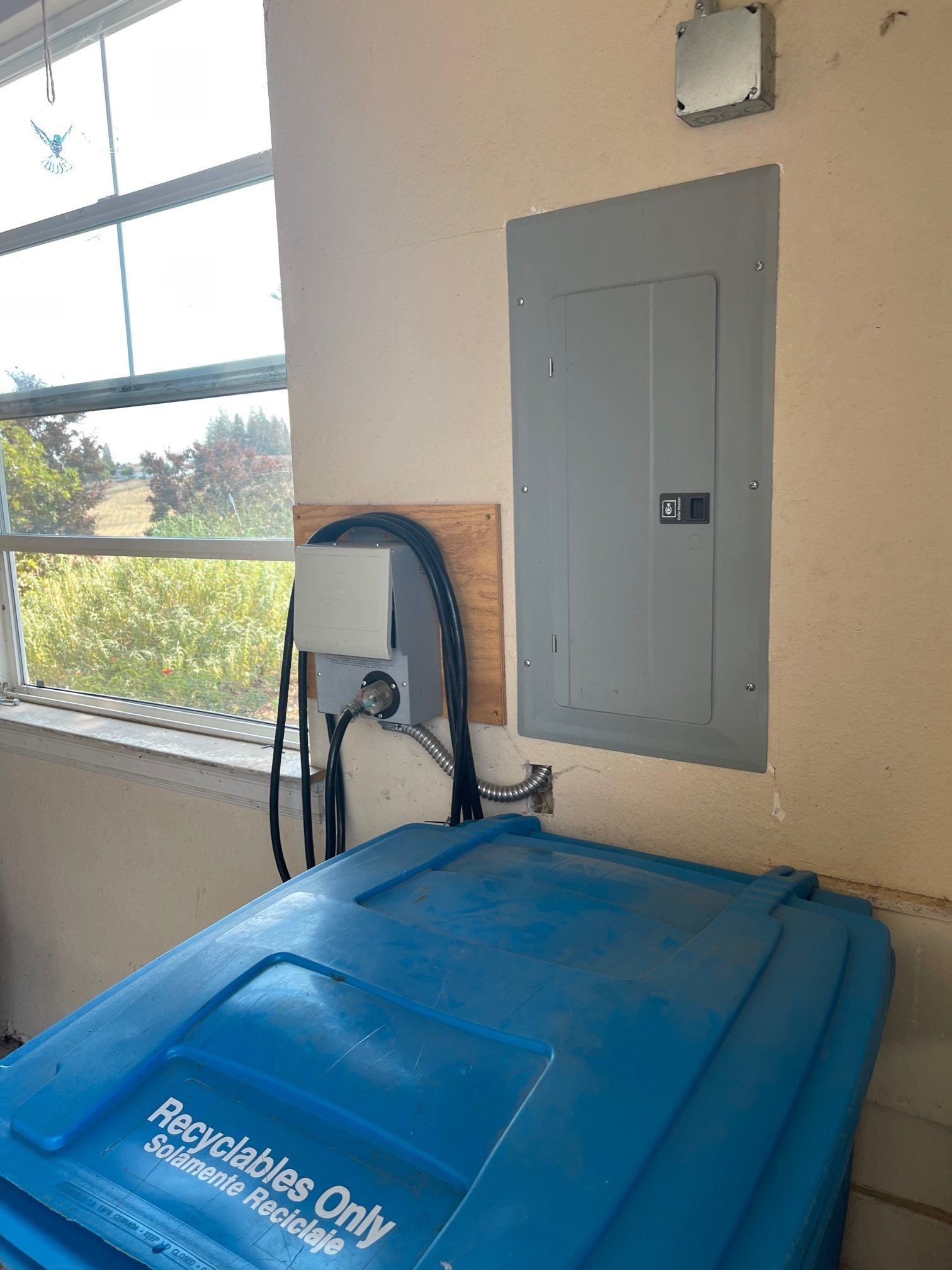 A blue trash can is sitting next to a window in a room.