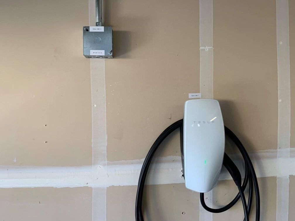 A tesla charging station is attached to a wall in a garage.