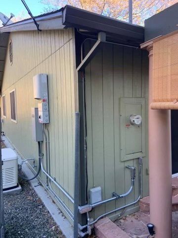 A house with a lot of wires on the side of it.