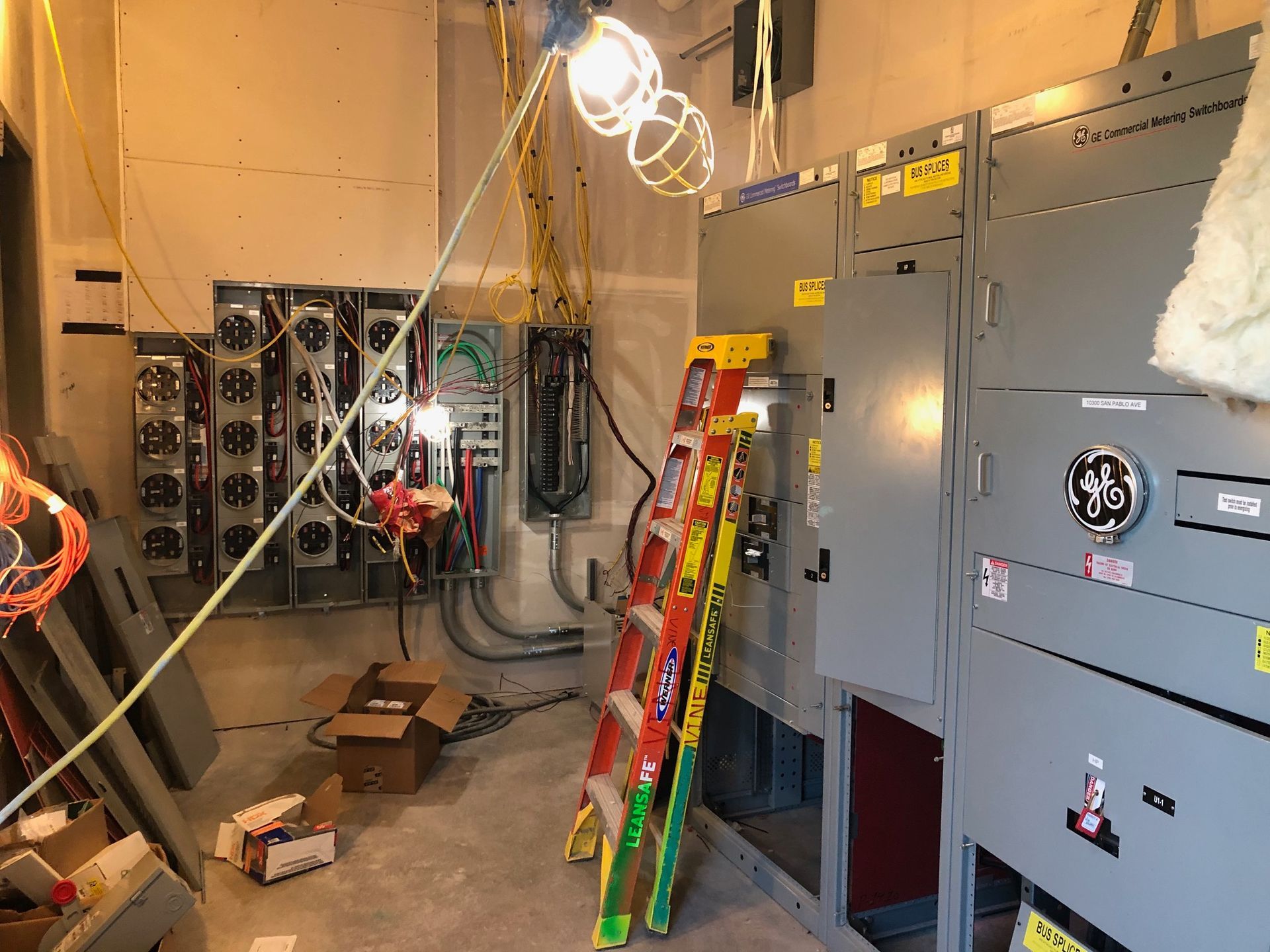 A room with a lot of electrical equipment and a ladder.