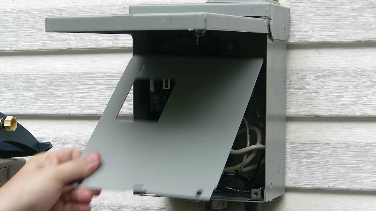 A person is opening a electrical box on a wall