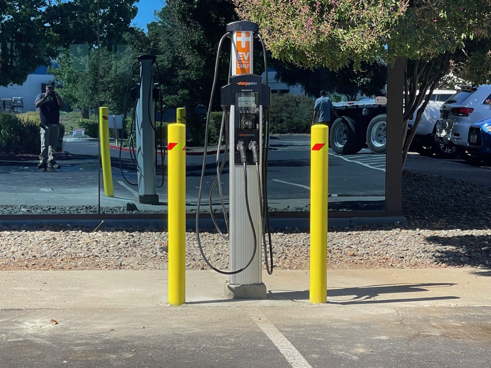 a charging station in a parking lot with yellow poles around it