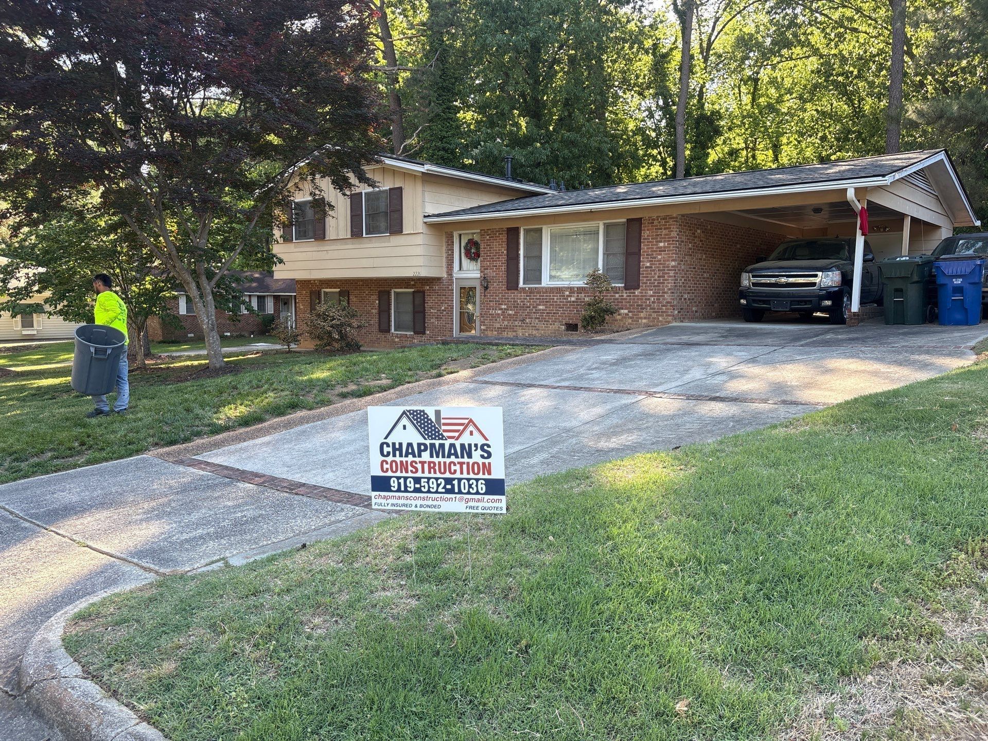House with a driveway, trees, and a real estate sign in the front yard