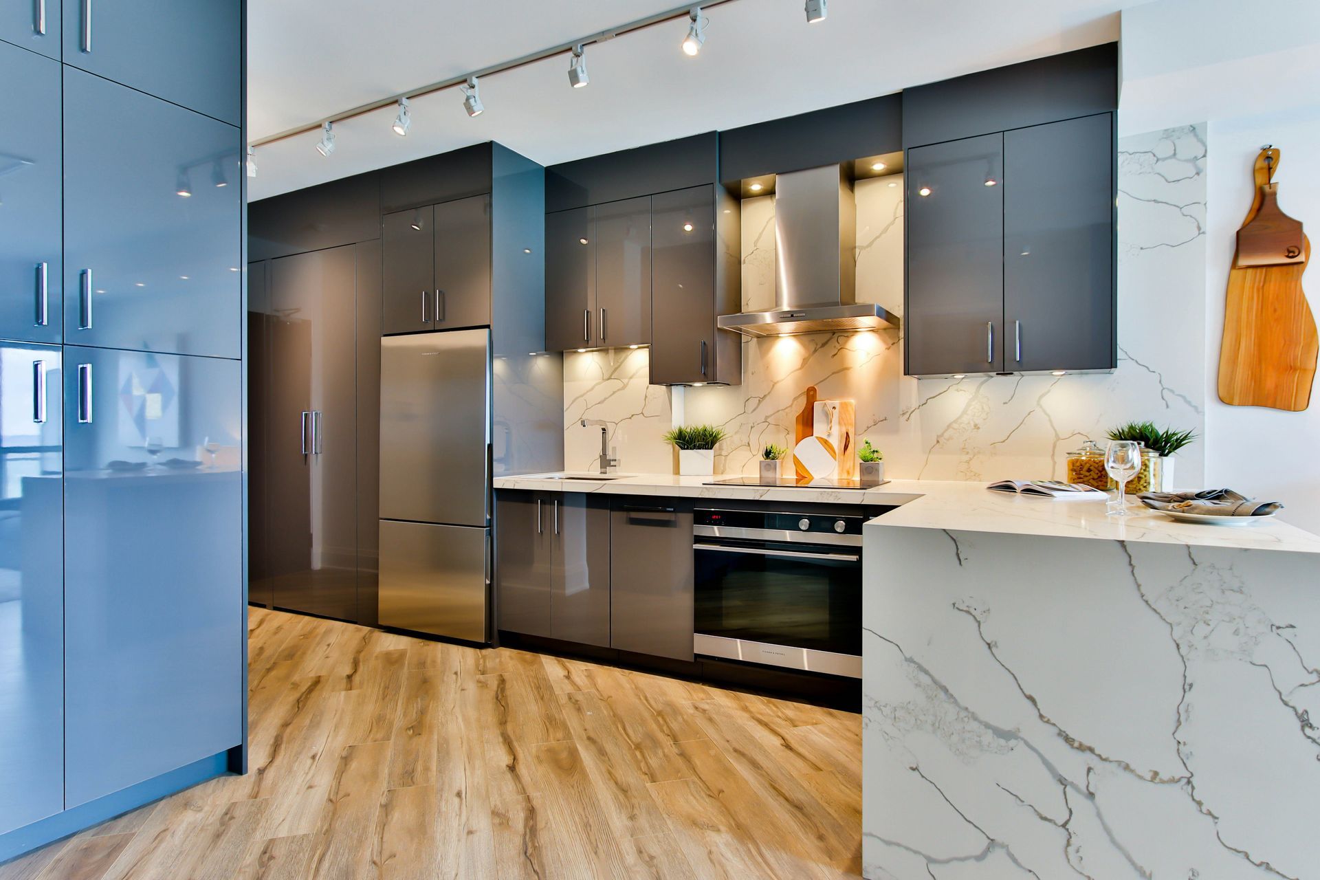 Modern kitchen with dark cabinets, marble island, wood floors, and blue refrigerator