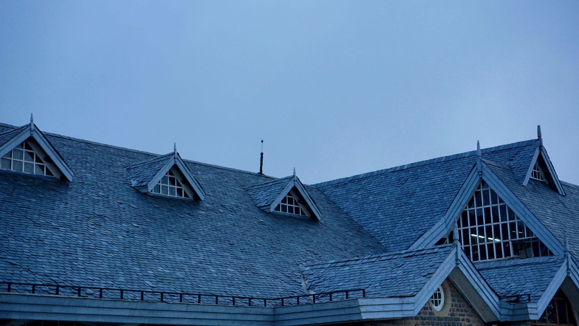 Snow-covered blue rooftops with dormer windows under a cloudy sky