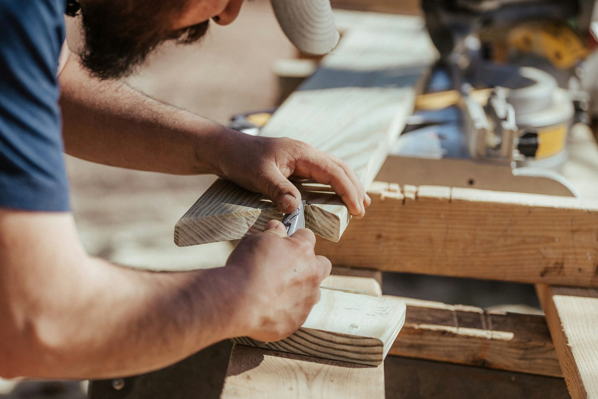 Hands sanding a wooden plank at a workbench in a woodworking shop