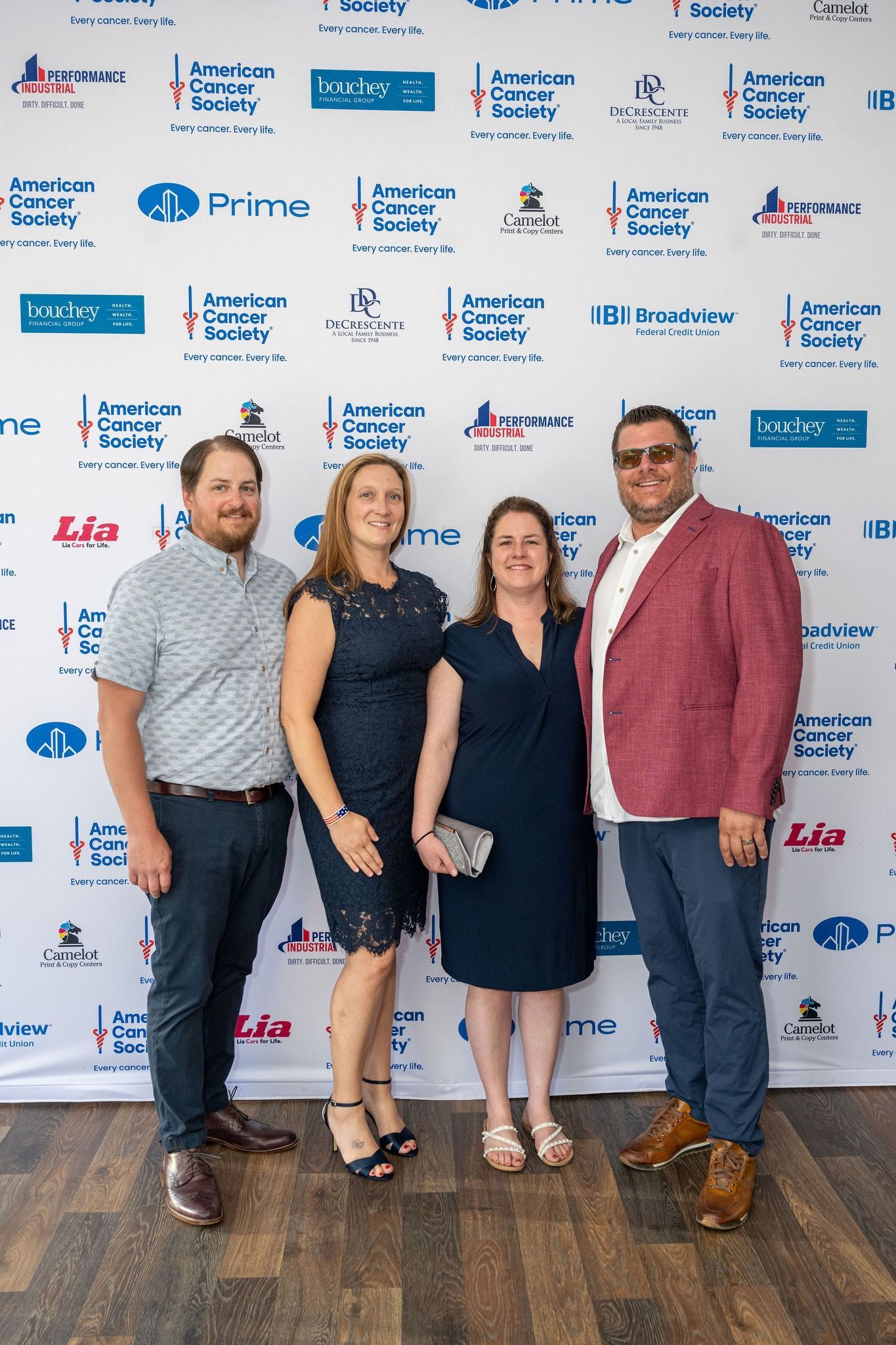 A group of people are posing for a picture in front of a wall with logos on it.