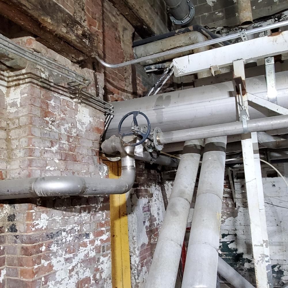 A bunch of pipes are connected to a brick wall