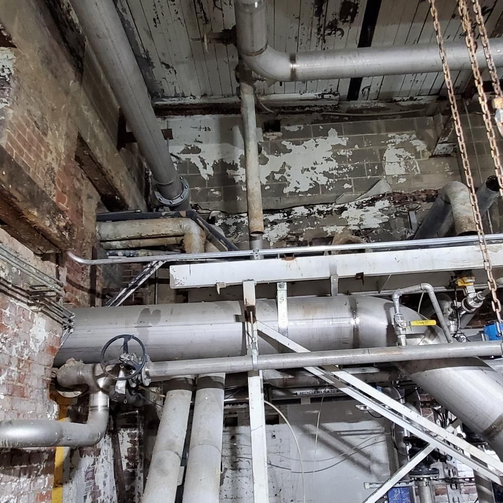 A bunch of pipes are hanging from the ceiling of a building