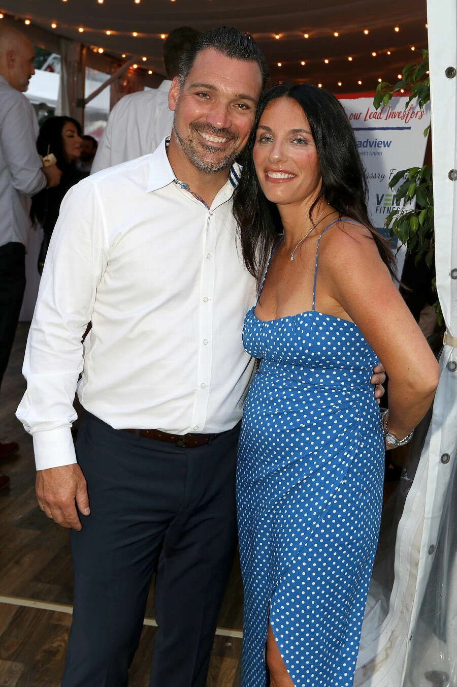 A man and a woman are posing for a picture at a party . the woman is wearing a blue dress.