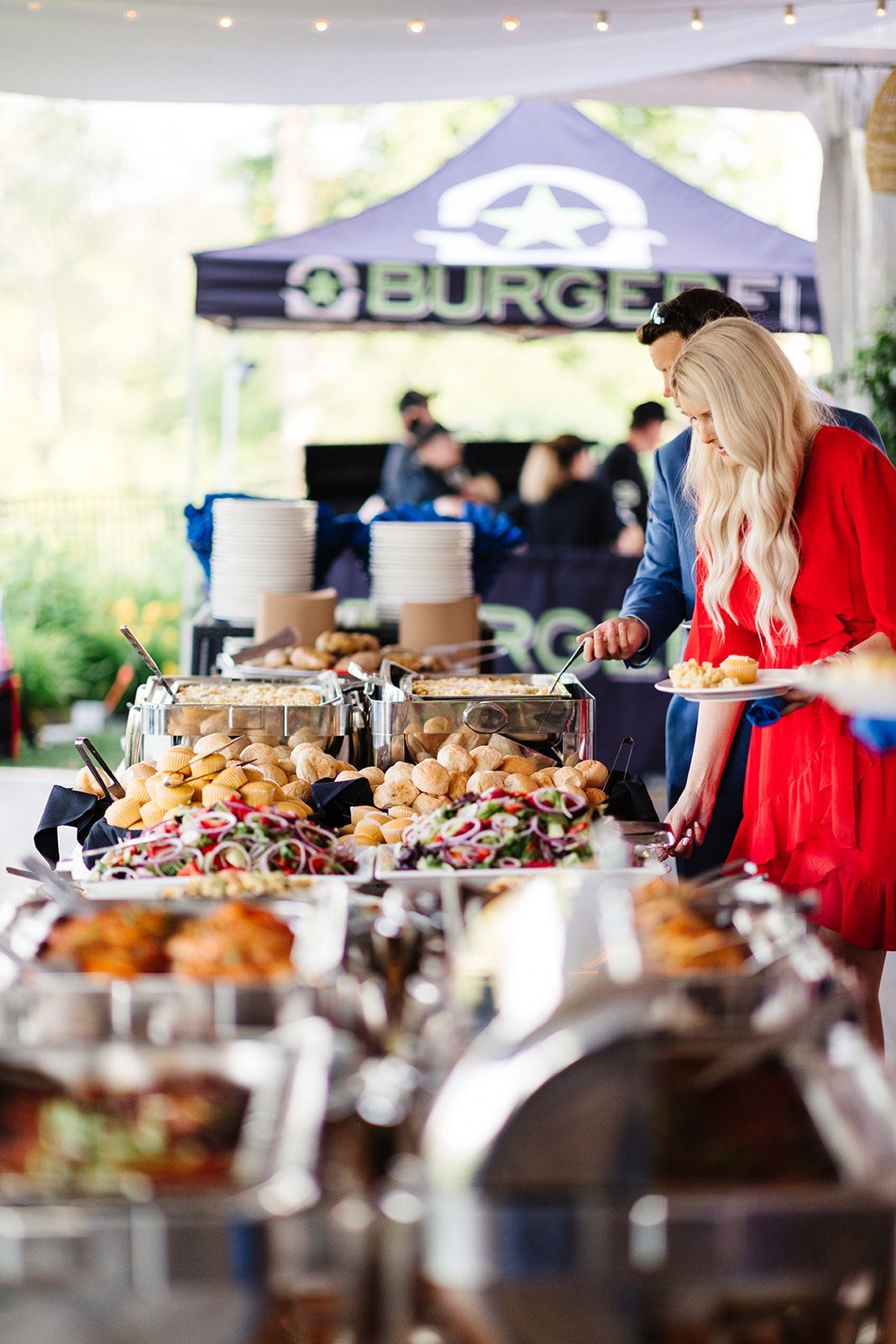 A woman in a red dress is standing in front of a buffet line.