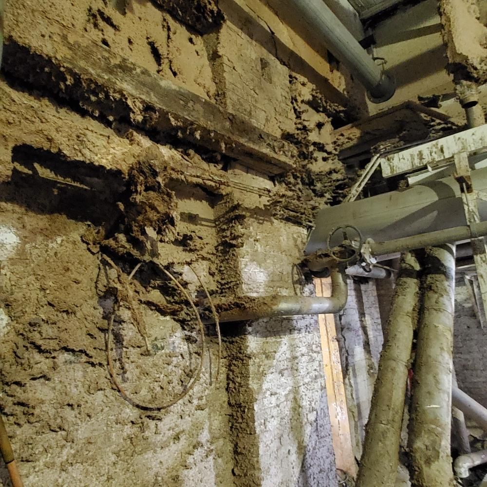 A dirty wall with pipes and wires and a sign that says ' a ' on it