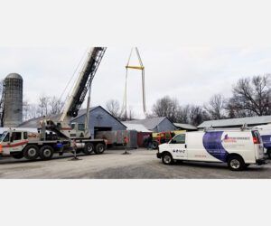 A crane is being lifted into a building next to a van.