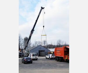 A crane is lifting a large object in a parking lot.