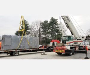 A crane is lifting a large container on a trailer.