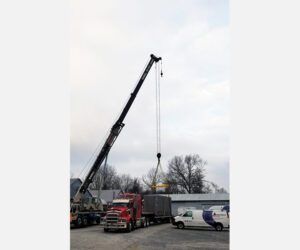 A truck is being lifted by a crane in a parking lot.